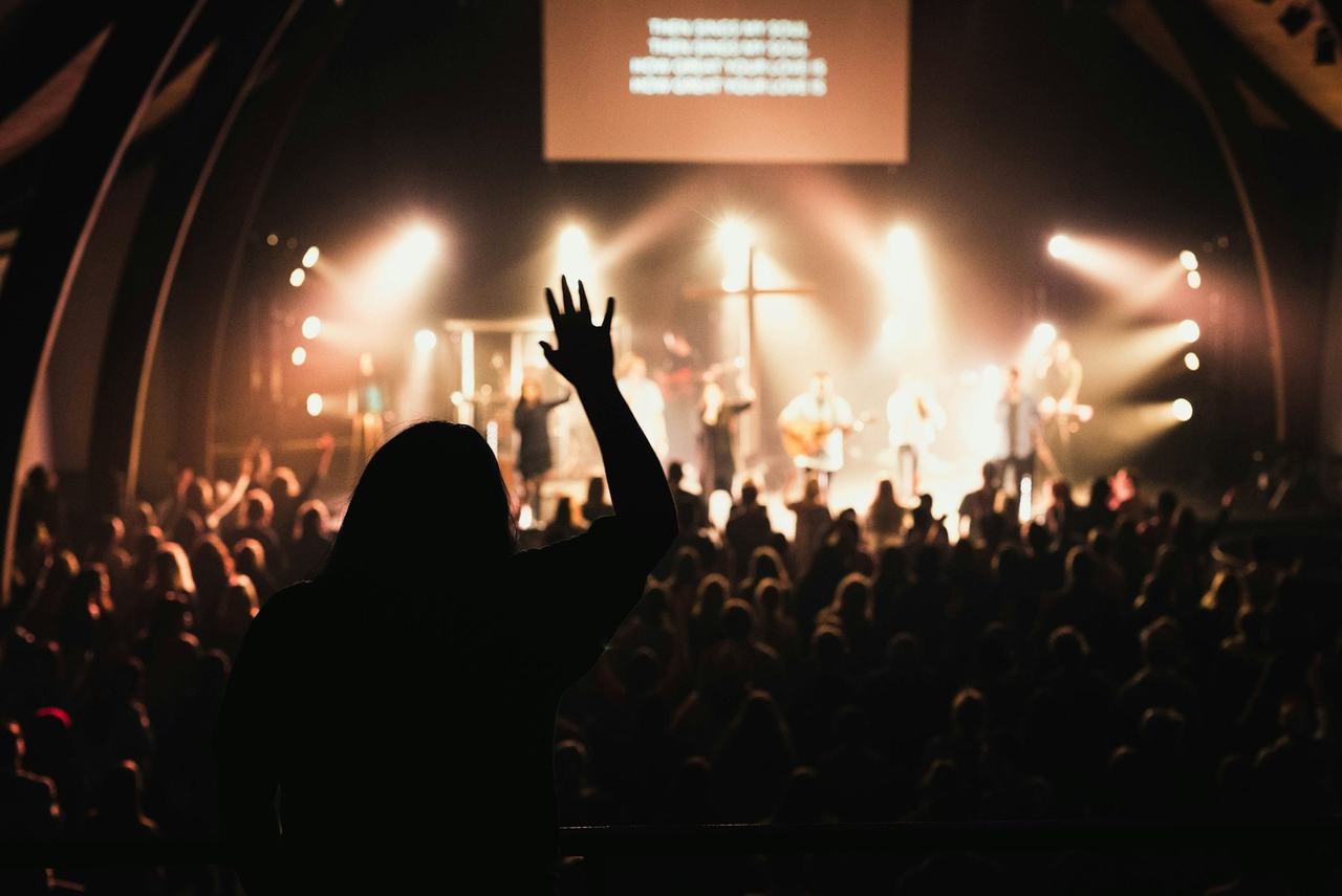 A congregation in worship, one hand raised toward the stage